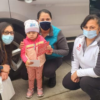 Three women wearing masks and a little girl looking at the camera.